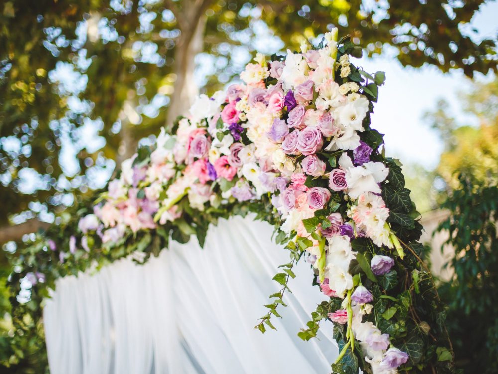 Wedding ceremony outdoors. Wedding arch in white with fresh flowers.