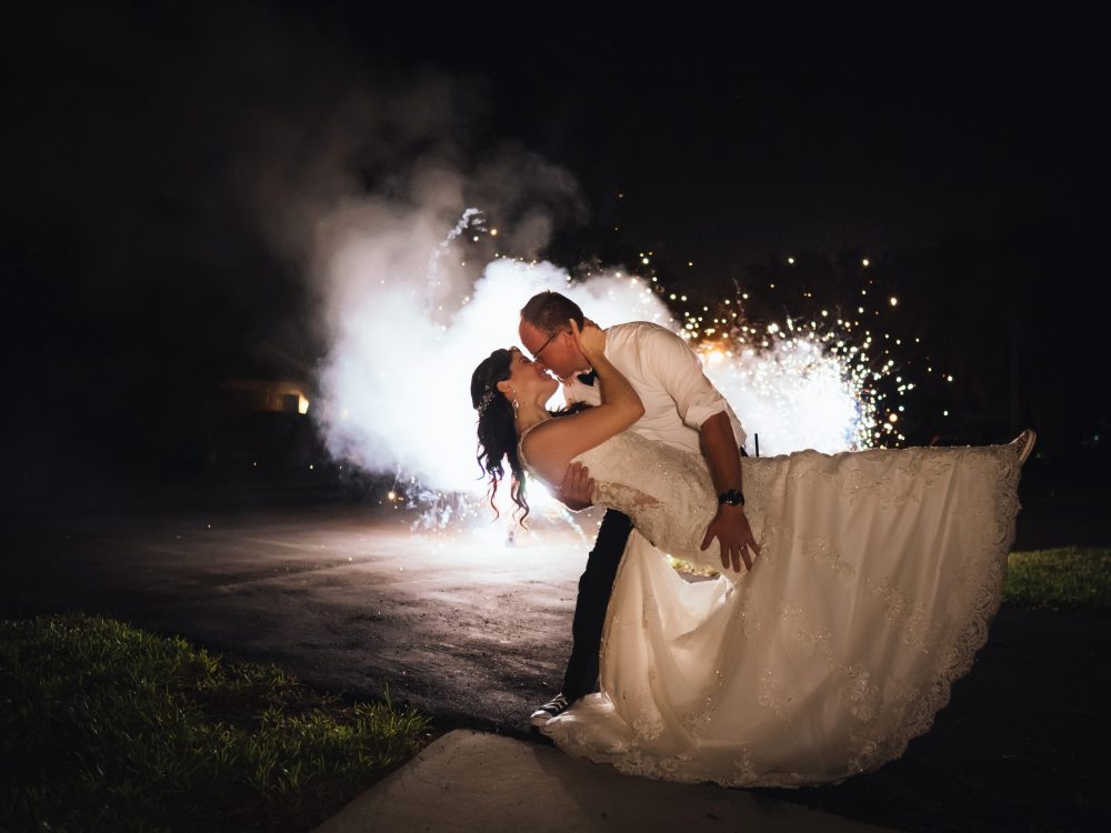 Newlyweds kissing with fireworks in the background