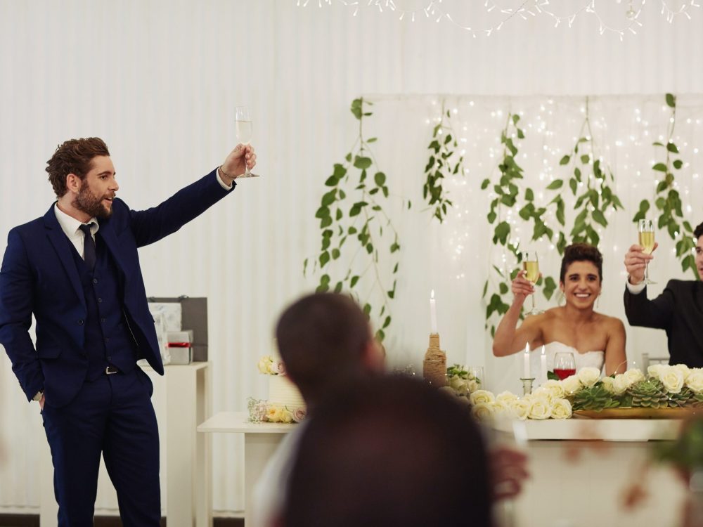 Shot of a young man giving a toast and speech at a wedding reception